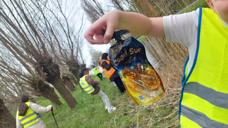 Kind heeft een vies drinkpakje vast die hij in de natuur heeft gevonden.